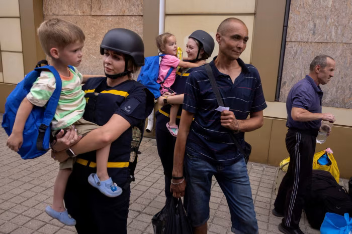 Працівники екстрених служб несуть дітей, оскільки місцеві жителі рятуються від наступу російських військ у Покровську © Thomas Peter/Reuters